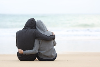 two teens with back to the camera holding each other